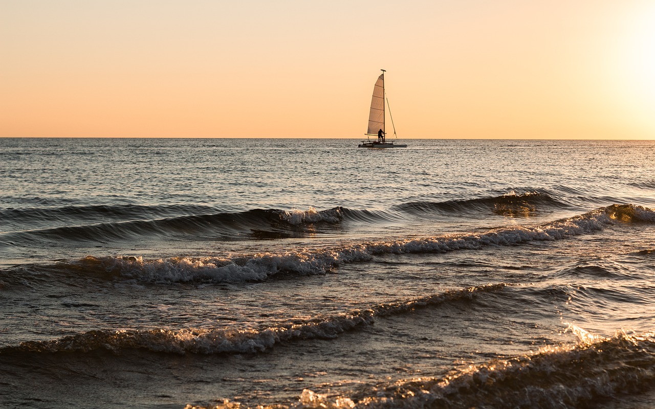 Foto de la playa con una persona en una tabla de windsurf