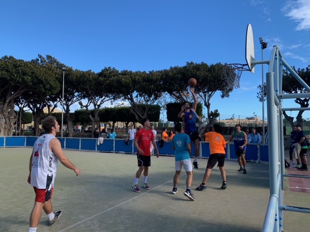 5 alumnos jugando al baloncesto con público alrdedor