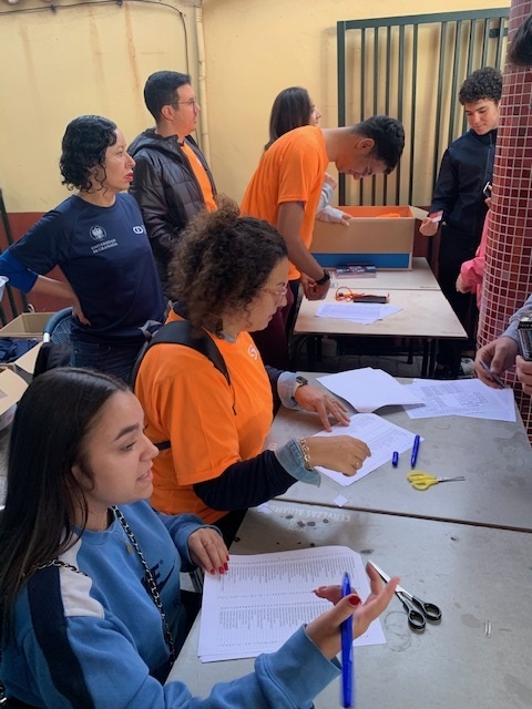 Profesores y alumnos sentados en una mesa tomando nota y entregando las acreditaciones