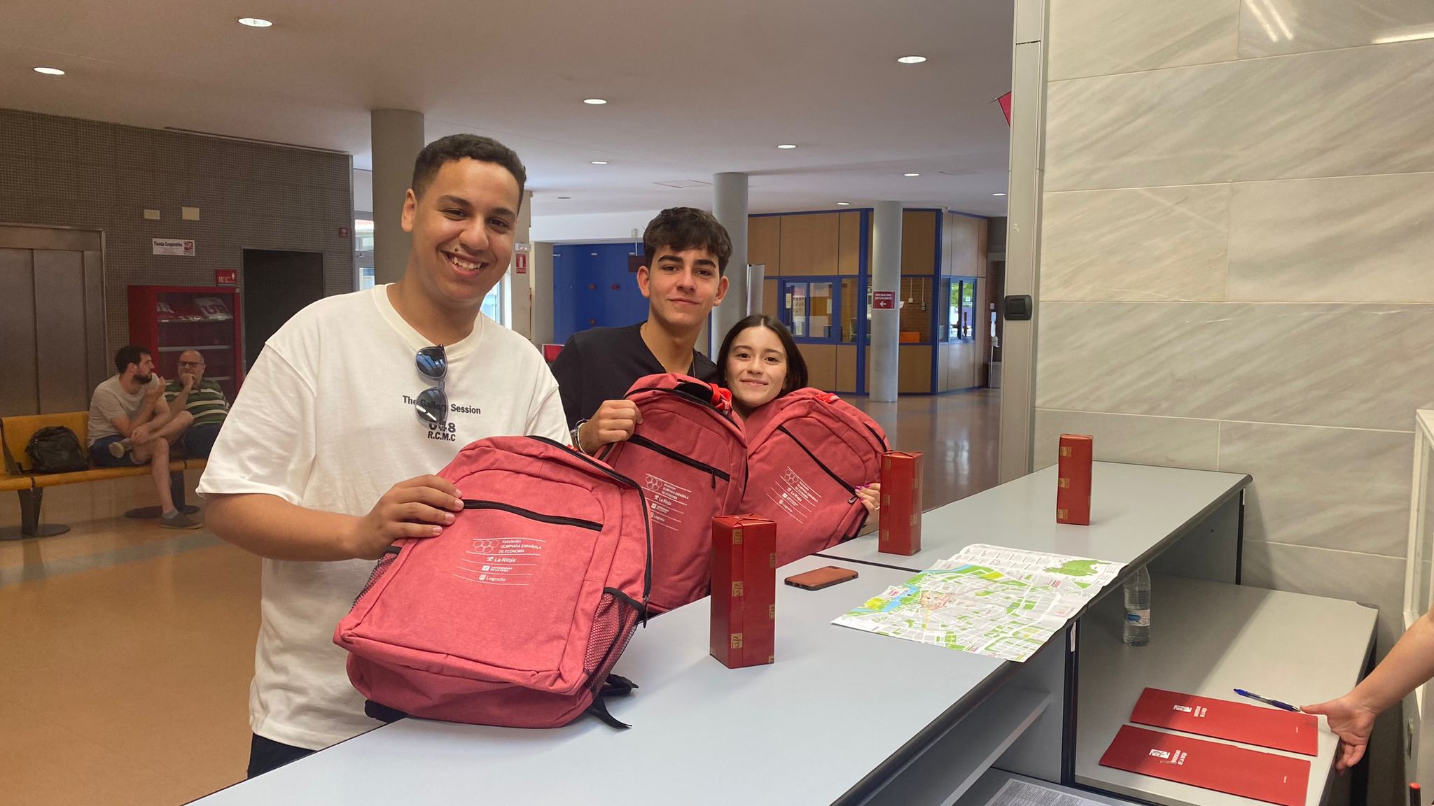 Tres finalistas fase local recogiendo acreditación mochilas y material de la Olimpiada