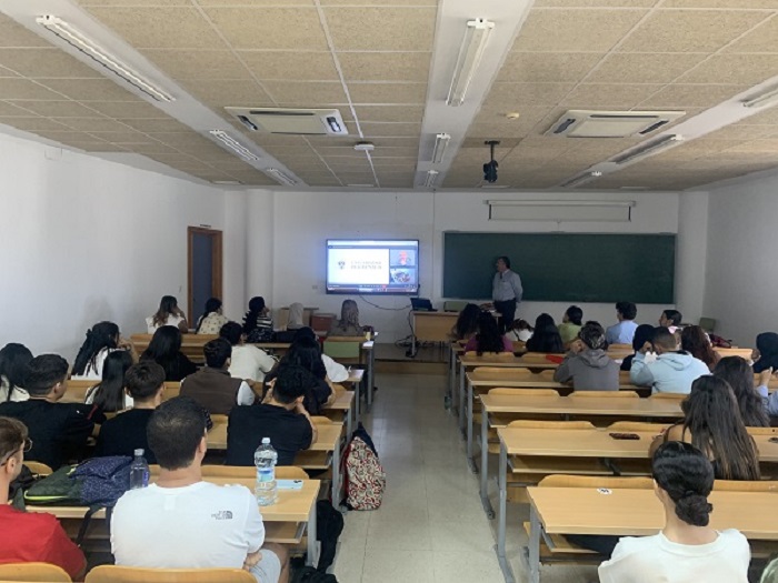 Foto aula presencial alumnos y profesor con pantalla virtual