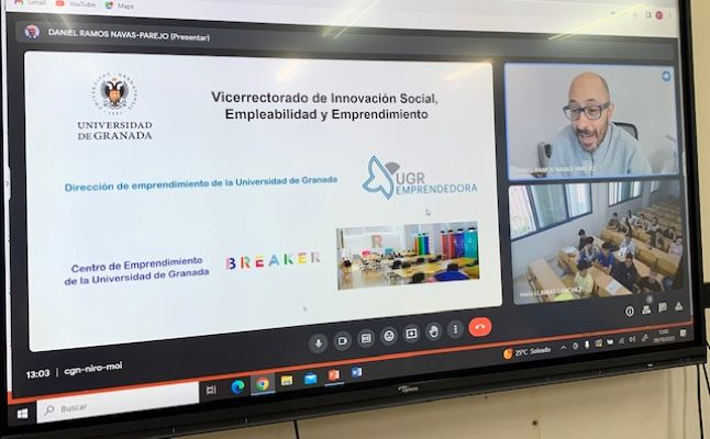 Visita a aulas de UGR emprendedora Fotografía a la pantalla donde se ha retransmitido la videollamada, en la que aparece el técnico de emprendimiento, el aula y la presentación presentada.